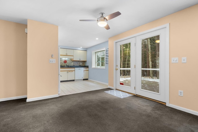 unfurnished living room with ceiling fan, light carpet, and sink