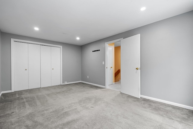 unfurnished bedroom with light colored carpet and a closet