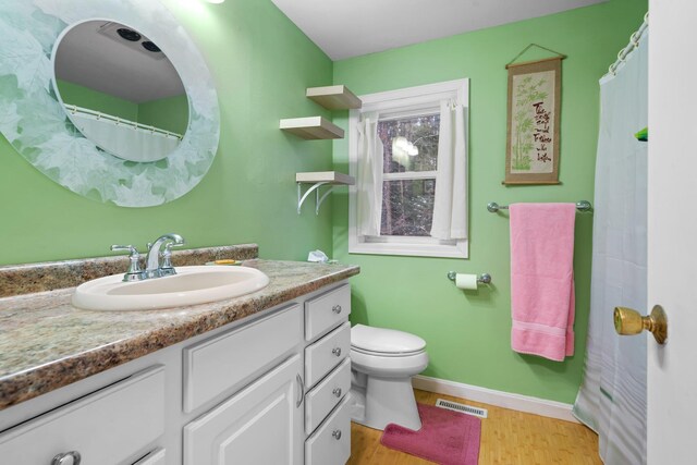 bathroom featuring toilet, wood-type flooring, and vanity