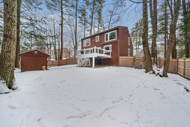 snow covered property featuring a wooden deck and a storage unit