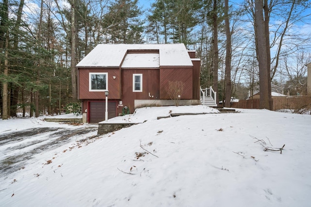 snow covered rear of property featuring a garage