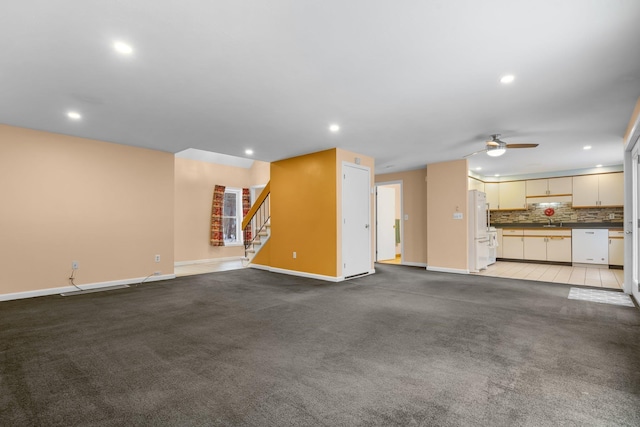 unfurnished living room featuring ceiling fan, light carpet, and sink