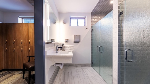 bathroom featuring a shower with shower door and sink