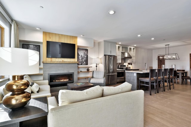 living room with light wood-type flooring, a large fireplace, and a notable chandelier