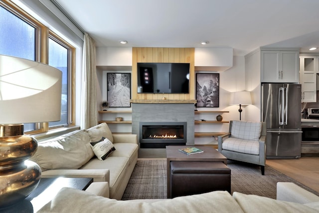 living room with hardwood / wood-style flooring, plenty of natural light, and a large fireplace