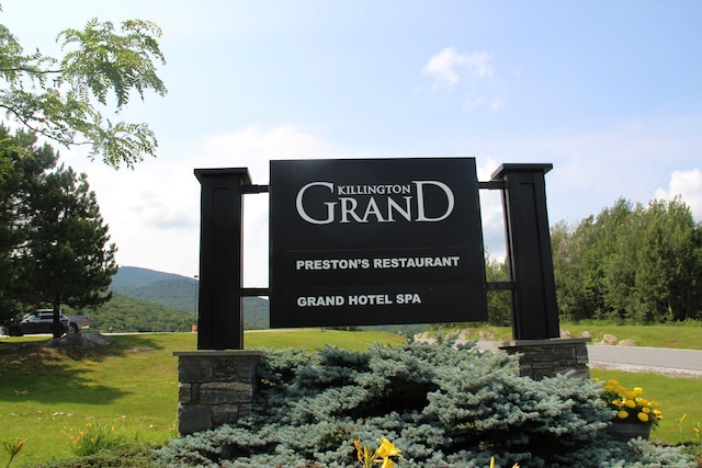 community / neighborhood sign featuring a lawn and a mountain view