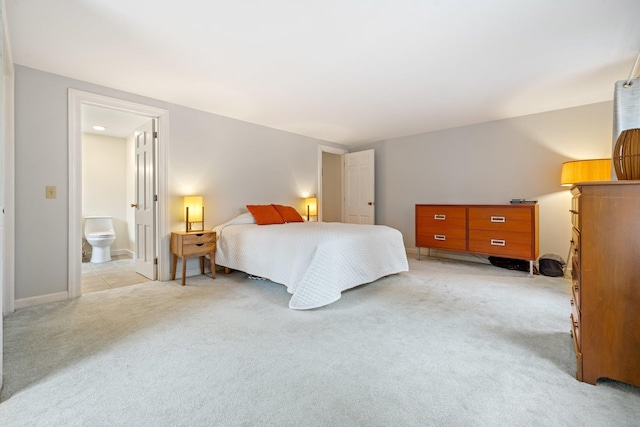 bedroom with ensuite bathroom and light carpet