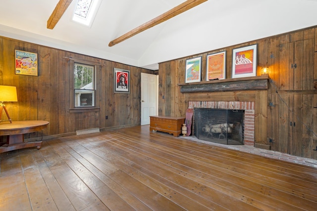 unfurnished living room featuring wood-type flooring, wooden walls, a fireplace, and lofted ceiling with skylight