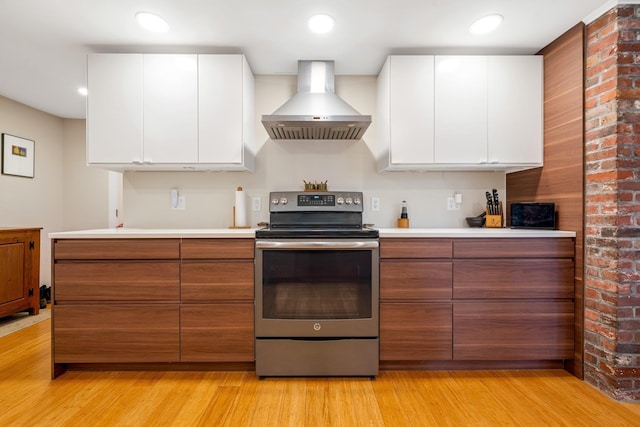 kitchen featuring electric range, exhaust hood, light hardwood / wood-style flooring, and white cabinetry