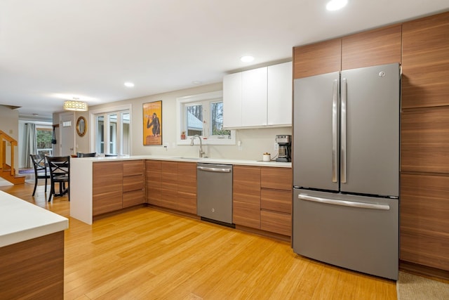 kitchen featuring sink, white cabinetry, light wood-type flooring, plenty of natural light, and appliances with stainless steel finishes