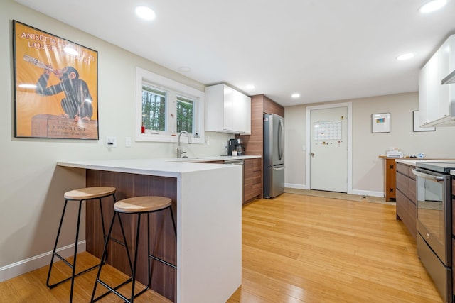 kitchen with white cabinets, a kitchen bar, appliances with stainless steel finishes, and kitchen peninsula