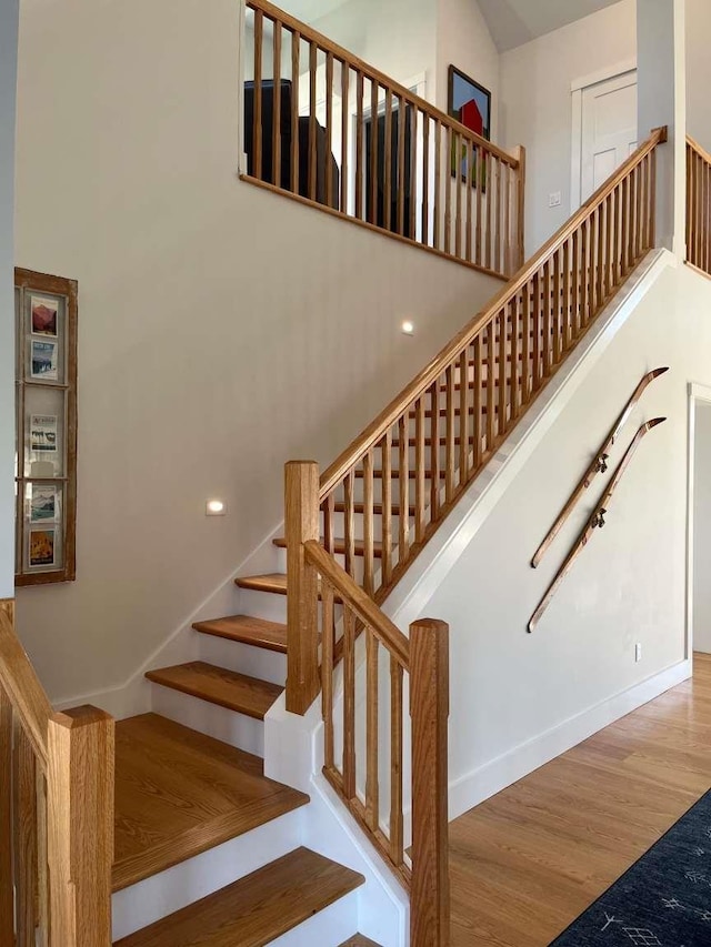 staircase with a high ceiling and hardwood / wood-style floors