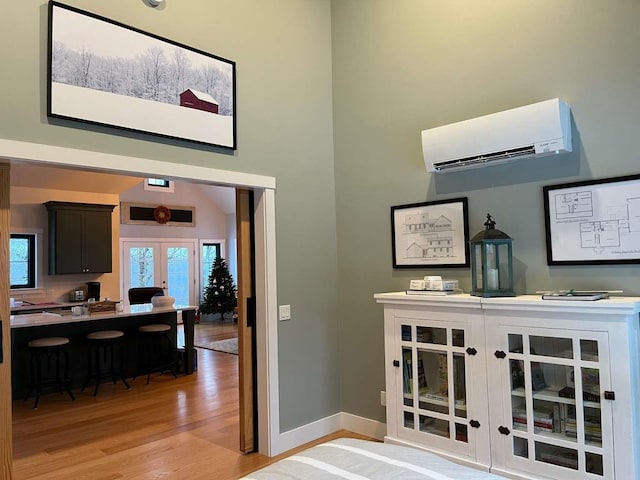 interior space with a wall mounted AC, french doors, and light hardwood / wood-style floors