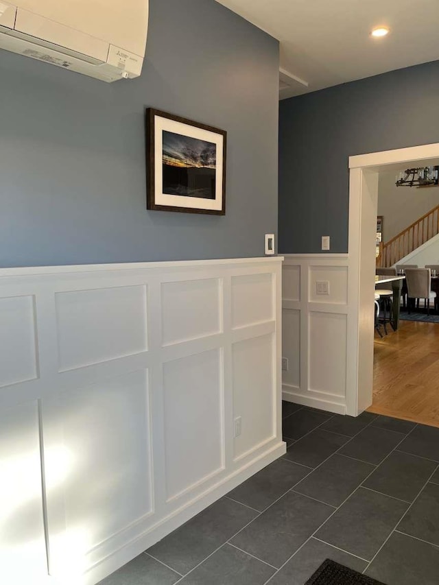 corridor featuring an AC wall unit and dark tile patterned flooring