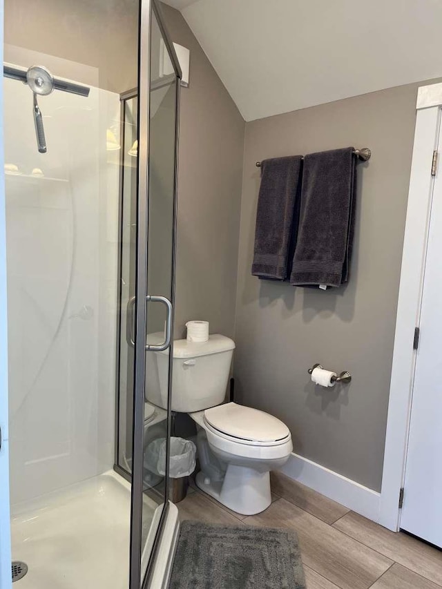 bathroom with vaulted ceiling, an enclosed shower, and toilet