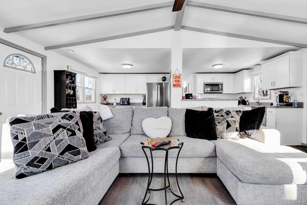 living room with sink, dark wood-type flooring, and vaulted ceiling with beams