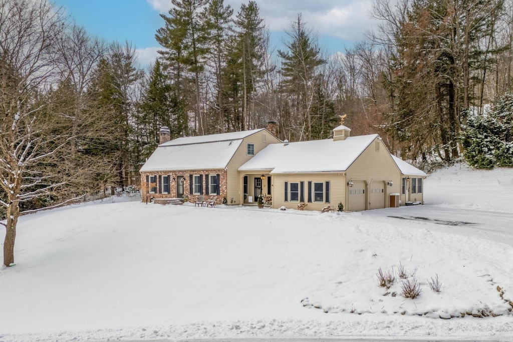 snow covered rear of property featuring a garage