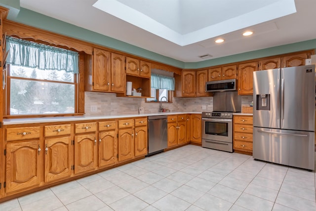 kitchen with tasteful backsplash, appliances with stainless steel finishes, light tile patterned floors, and a wealth of natural light