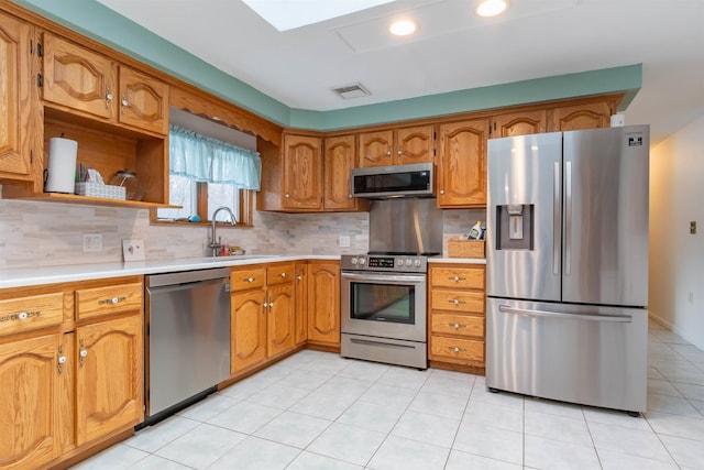 kitchen with stainless steel appliances, light tile patterned floors, decorative backsplash, and sink