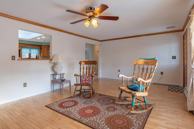 sitting room featuring a skylight, ceiling fan, ornamental molding, and light hardwood / wood-style flooring