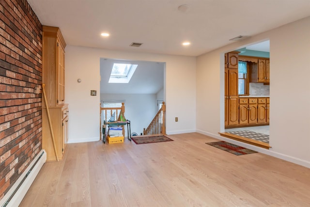 entrance foyer featuring baseboard heating, light wood-type flooring, and a skylight