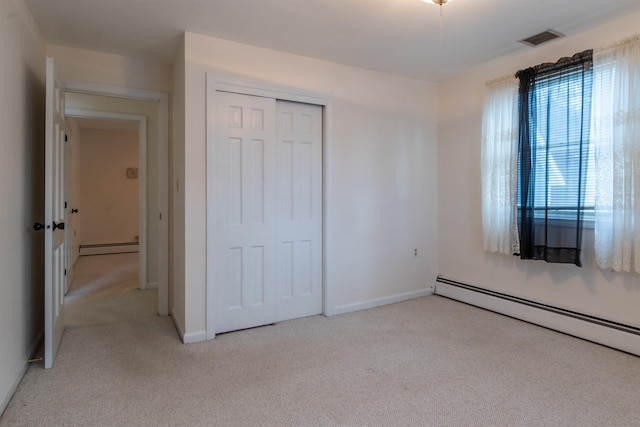 unfurnished bedroom with a closet, a baseboard radiator, and light carpet