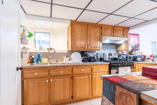 kitchen with sink, a paneled ceiling, stainless steel gas stove, and light tile patterned flooring