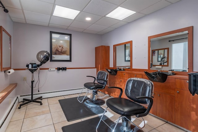 exercise room with baseboard heating, a drop ceiling, and light tile patterned flooring