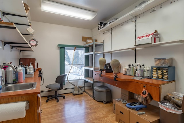 office space with a baseboard heating unit, light wood-type flooring, and sink