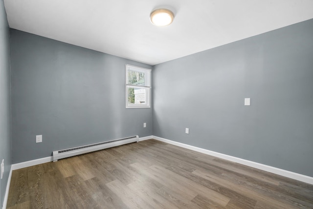 empty room with wood-type flooring and a baseboard heating unit