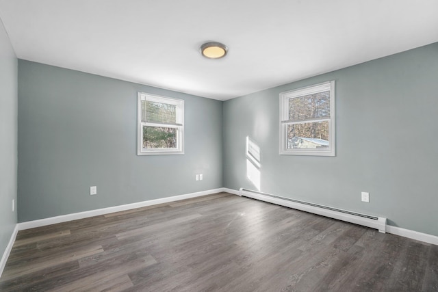 spare room with dark hardwood / wood-style flooring, a baseboard radiator, and a wealth of natural light