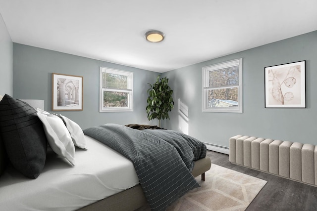 bedroom with a baseboard heating unit, radiator heating unit, and dark wood-type flooring