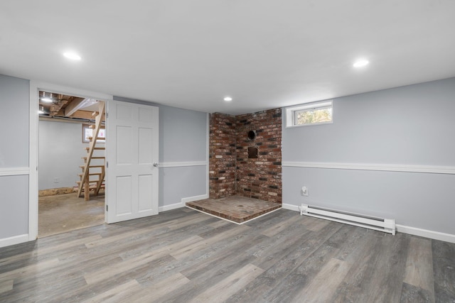 basement featuring a baseboard heating unit and wood-type flooring