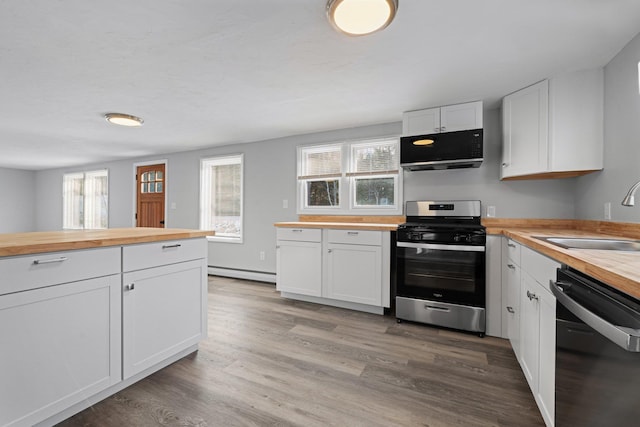 kitchen featuring black appliances, wooden counters, baseboard heating, white cabinetry, and sink