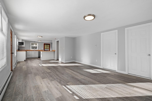 unfurnished living room featuring baseboard heating and light hardwood / wood-style flooring