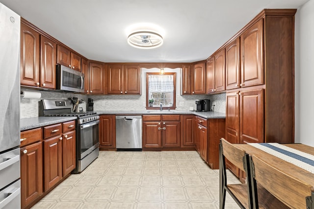 kitchen featuring light stone counters, appliances with stainless steel finishes, decorative backsplash, and sink