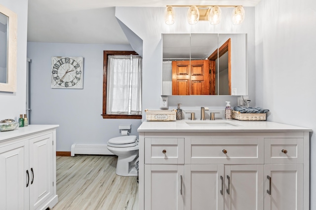 bathroom featuring baseboard heating, vanity, hardwood / wood-style flooring, and toilet