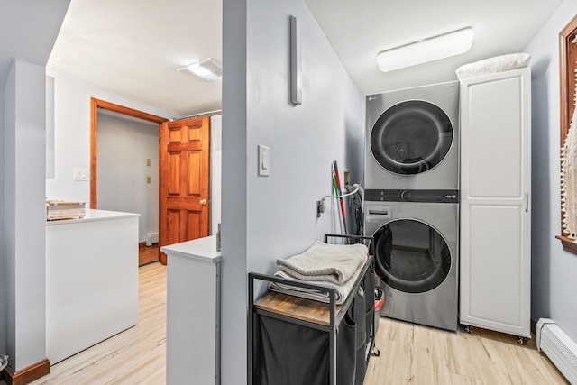 washroom featuring light hardwood / wood-style flooring, cabinets, stacked washer / dryer, and a baseboard heating unit