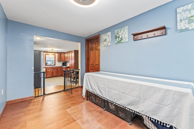 bedroom with light hardwood / wood-style floors and stainless steel fridge