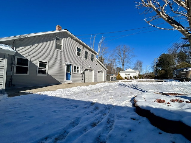 snow covered rear of property with a garage