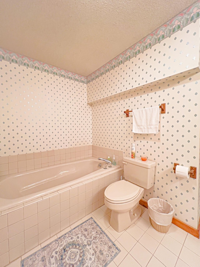 bathroom with a relaxing tiled tub, a textured ceiling, tile patterned floors, and toilet