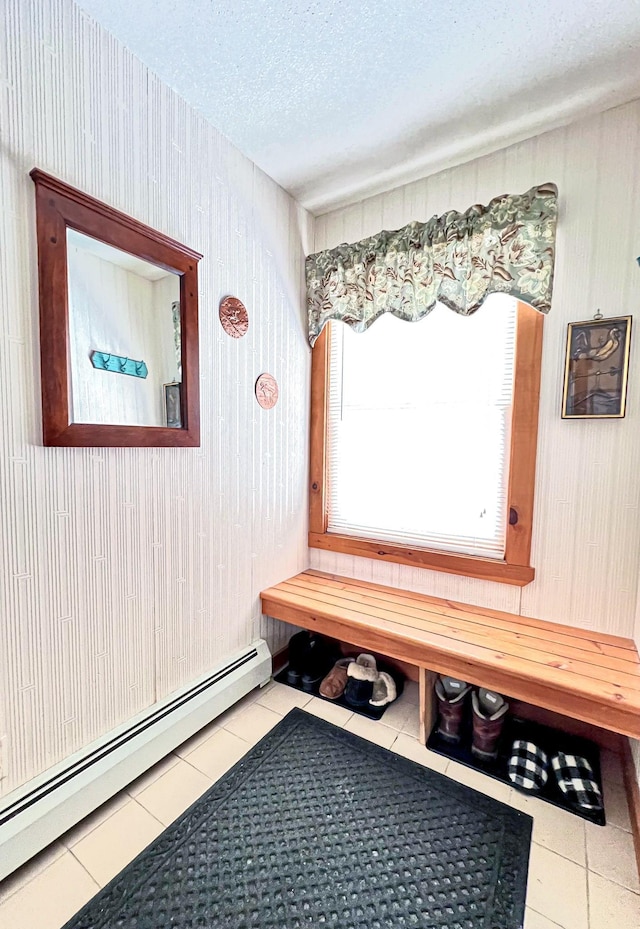 mudroom featuring a textured ceiling, wooden walls, a baseboard radiator, and tile patterned floors