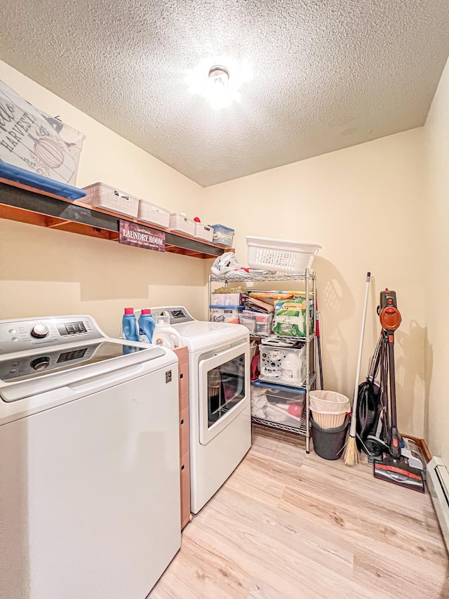 laundry area featuring separate washer and dryer, light wood-type flooring, a textured ceiling, and a baseboard heating unit