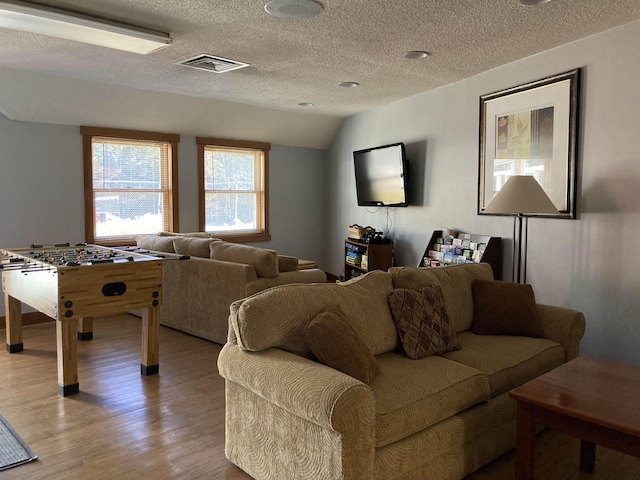 living room featuring a textured ceiling, vaulted ceiling, and light hardwood / wood-style flooring