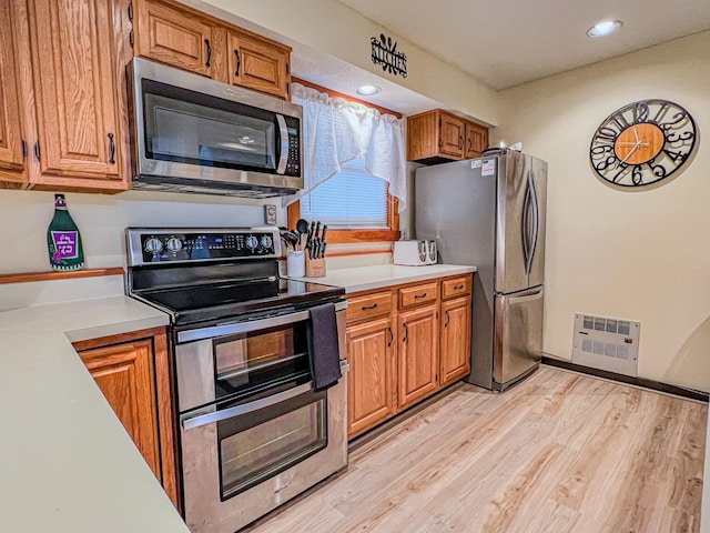 kitchen featuring appliances with stainless steel finishes and light hardwood / wood-style flooring