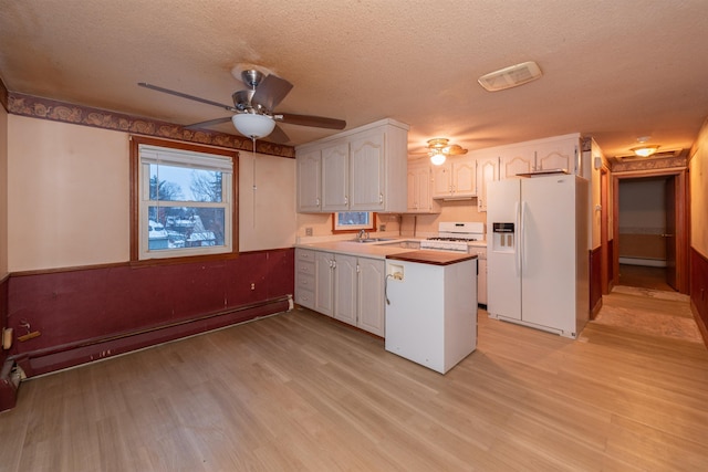 kitchen with white appliances, kitchen peninsula, a textured ceiling, and white cabinets