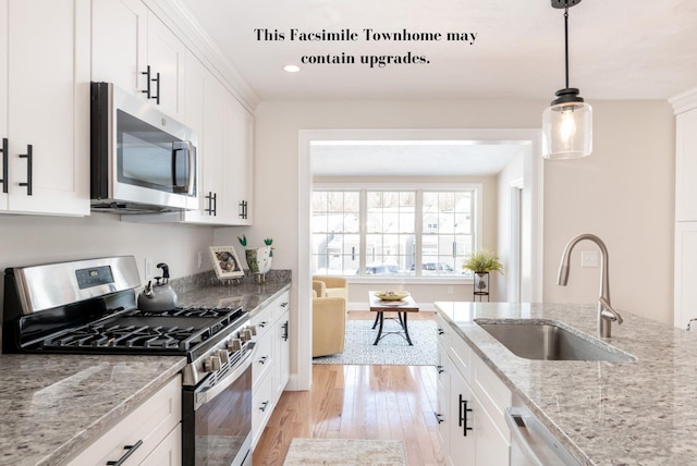 kitchen featuring sink, white cabinets, light stone counters, and appliances with stainless steel finishes