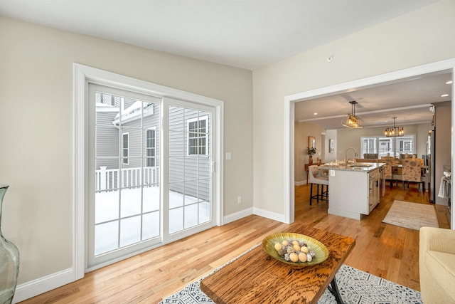 living room with sink, a notable chandelier, and light hardwood / wood-style flooring