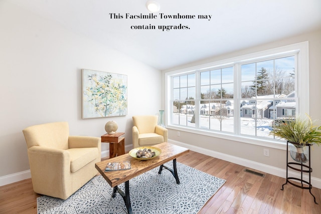 sitting room with lofted ceiling, light hardwood / wood-style floors, and a wealth of natural light