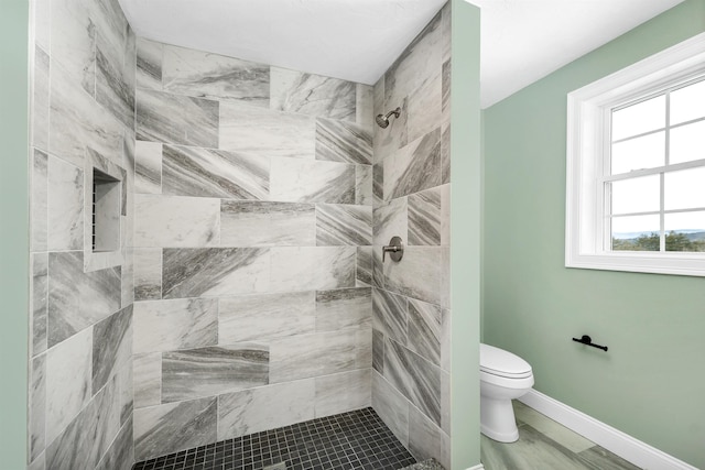 bathroom featuring toilet and a tile shower